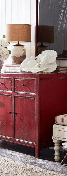 a room with a dresser, chair and lamp in it's centerpieces