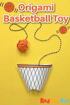 an origami basketball toy hanging from a string on a yellow background with red balls