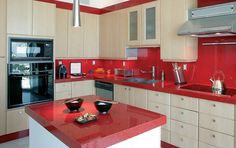 a modern kitchen with red counter tops and white cabinets, along with stainless steel appliances