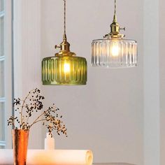 two glass pendant lights hanging over a table