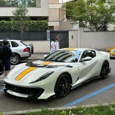 a white and yellow sports car parked on the side of the road with people walking by