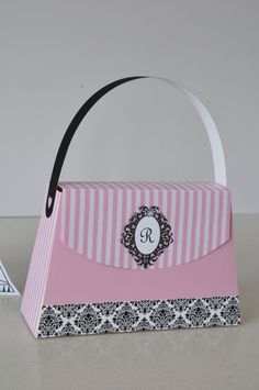 a pink and white striped paper bag with a monogrammed bow on the front