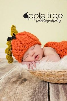 a baby wearing an orange knitted hat laying in a basket