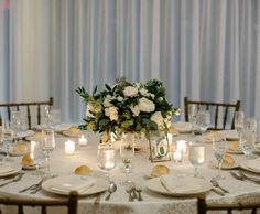 the table is set with white flowers and candles for an elegant wedding reception or special event