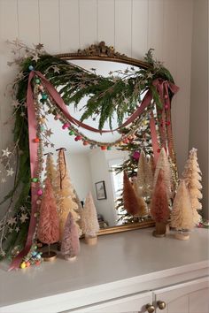 a mirror sitting on top of a mantle covered in christmas trees