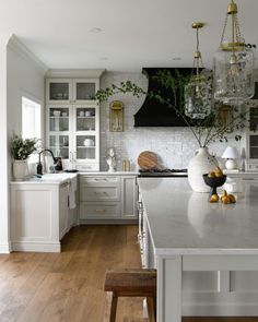 a large kitchen with white cabinets and wooden flooring, along with an island in the middle