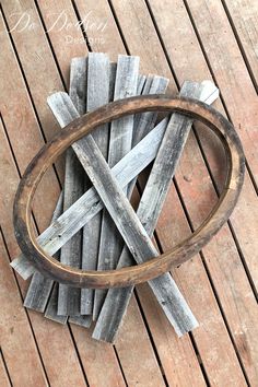 a circular wooden object sitting on top of a wooden floor next to a pile of wood planks