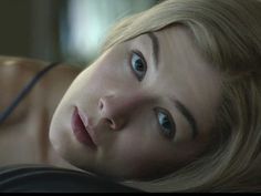 a woman laying down with her head resting on her hand and looking at the camera