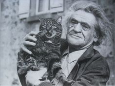 an old man holding a cat in front of a building with the caption, i am not sure what this image is