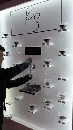 a man standing in front of a display filled with wine glasses