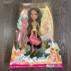 a barbie doll is sitting next to a surfboard on a wooden table with other dolls