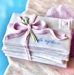 a stack of folded cards with a pink ribbon tied around it on top of a table