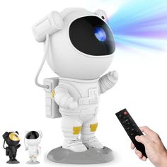 a hand holding a remote control next to an image of a white robot with blue eyes