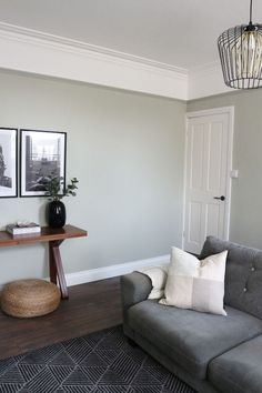 a living room with a gray couch and two pictures on the wall next to it