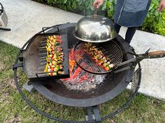 a man is cooking on an outdoor grill with skewered vegetables and meats