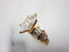 "A vintage 14k gold and CZ engagement ring, with accent stones set in the wide shoulders of the ring. Marked \"14k MUS CZ\" and acid tested, also marked with something else I cannot make out. A US size 9. Actual packaging will vary depending on item/s purchased and tape pattern available. Props/boxes shown in photos are for display purposes only, not included in this listing. As always, satisfaction is guaranteed. Thanks for shopping Vintage In Bloom More rings: http://www.etsy.com/shop/VintageI Gold Marquise Wedding Ring With Accent Stones, Wedding Topaz Ring With Center Stone And Baguette Cut, Art Deco Gold Diamond Ring With Accent Stones, Gold Art Deco Diamond Ring With Accent Stones, Gold Marquise Cluster Ring With Accent Stones, Gold Marquise Cut Rings With Accent Stones, Marquise Cut Topaz Ring With Accent Stones For Anniversary, Vintage Marquise Cut Rings With Accent Stones, Vintage Marquise Cut Ring With Accent Stones