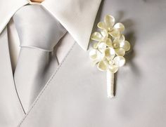 a close up of a white tie and flower brooch on a man's lapel