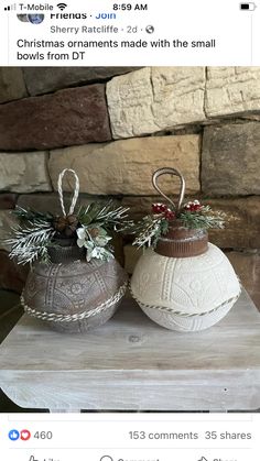 two christmas ornaments sitting on top of a wooden table next to a stone wall and brick wall