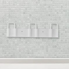 a white shelf with three bags on it in front of a brick wall and floor