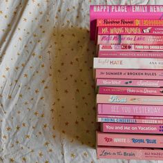 a stack of books sitting on top of a bed next to a white sheet with gold stars