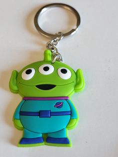 a green and blue toy character keychain sitting on top of a white surface