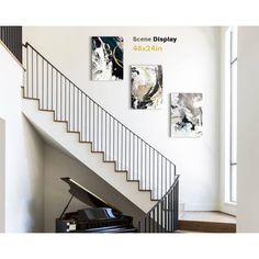 a grand piano sitting in front of a stair case next to a wall with paintings on it