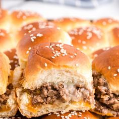 several hamburger sliders stacked on top of each other with sesame seed sprinkles