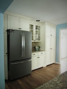 a kitchen with white cabinets and stainless steel refrigerator