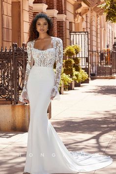 a woman in a white wedding dress standing on the sidewalk