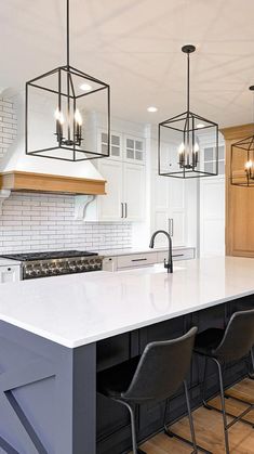 a kitchen island with four chairs and lights hanging from it's ceiling over the counter