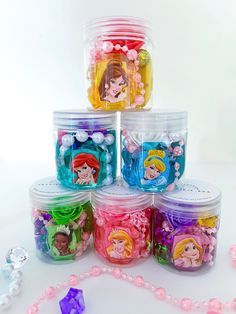 there are many little princesses in the plastic containers on the table with bead necklaces