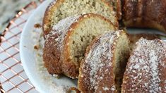 a white plate topped with slices of cake covered in powdered sugar on top of a metal rack