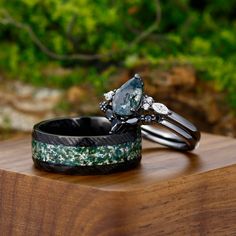 two wedding rings sitting on top of a wooden table next to another piece of jewelry