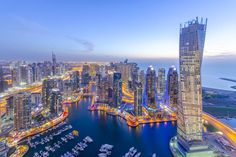 an aerial view of the city skyline at night, with skyscrapers and boats in the water