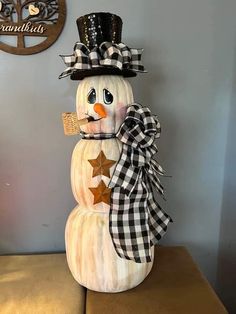 a snowman made out of wood with a black and white checkered hat on top