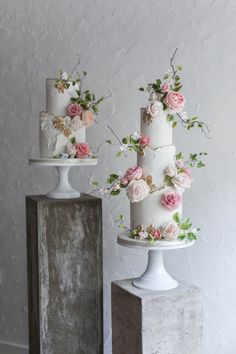 three tiered wedding cakes with pink flowers on top and white frosting, sitting next to each other