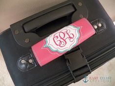 a black suitcase with a pink handle and monogrammed initials