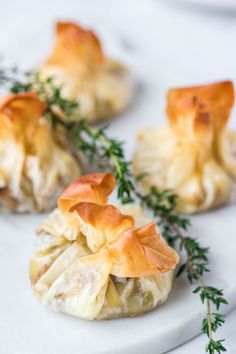 small appetizers are arranged on a white plate with green garnishes