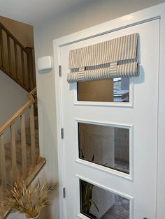 a white door with three windows on each side and a plant in the corner next to it