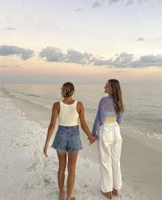 two women walking on the beach holding hands