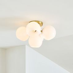 a ceiling light with five white balls hanging from it's center point in an empty room