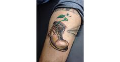 a man with a tattoo on his arm has a boot and a plant growing out of it