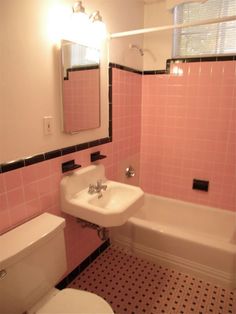 a bathroom with pink tiles on the walls and black and white flooring in it