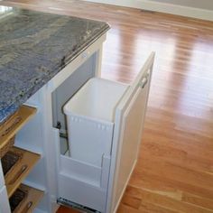 an open refrigerator in the middle of a kitchen with wood floors and windows behind it