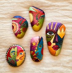 four painted rocks sitting on top of a white sheet