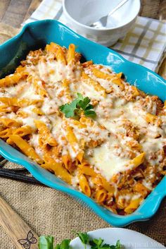 a blue casserole dish filled with pasta and cheese