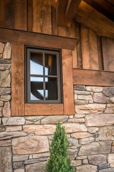 a window on the side of a stone building with a potted plant next to it