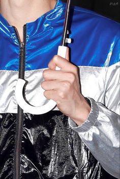 a man holding an umbrella in his hand while wearing a shiny jacket and silver pants