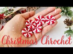 three red and white candy canes sitting in someone's hand next to christmas decorations