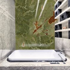 a bath tub sitting next to a wall with green marble on the top and bottom